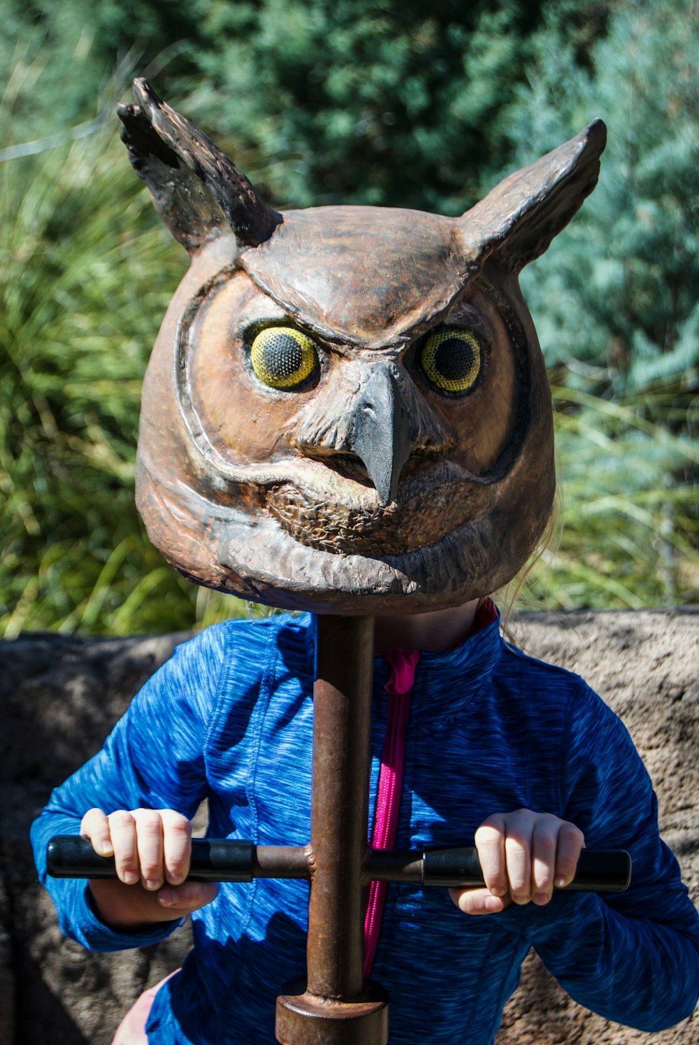 a young boy wearing an owl mask holding a stick