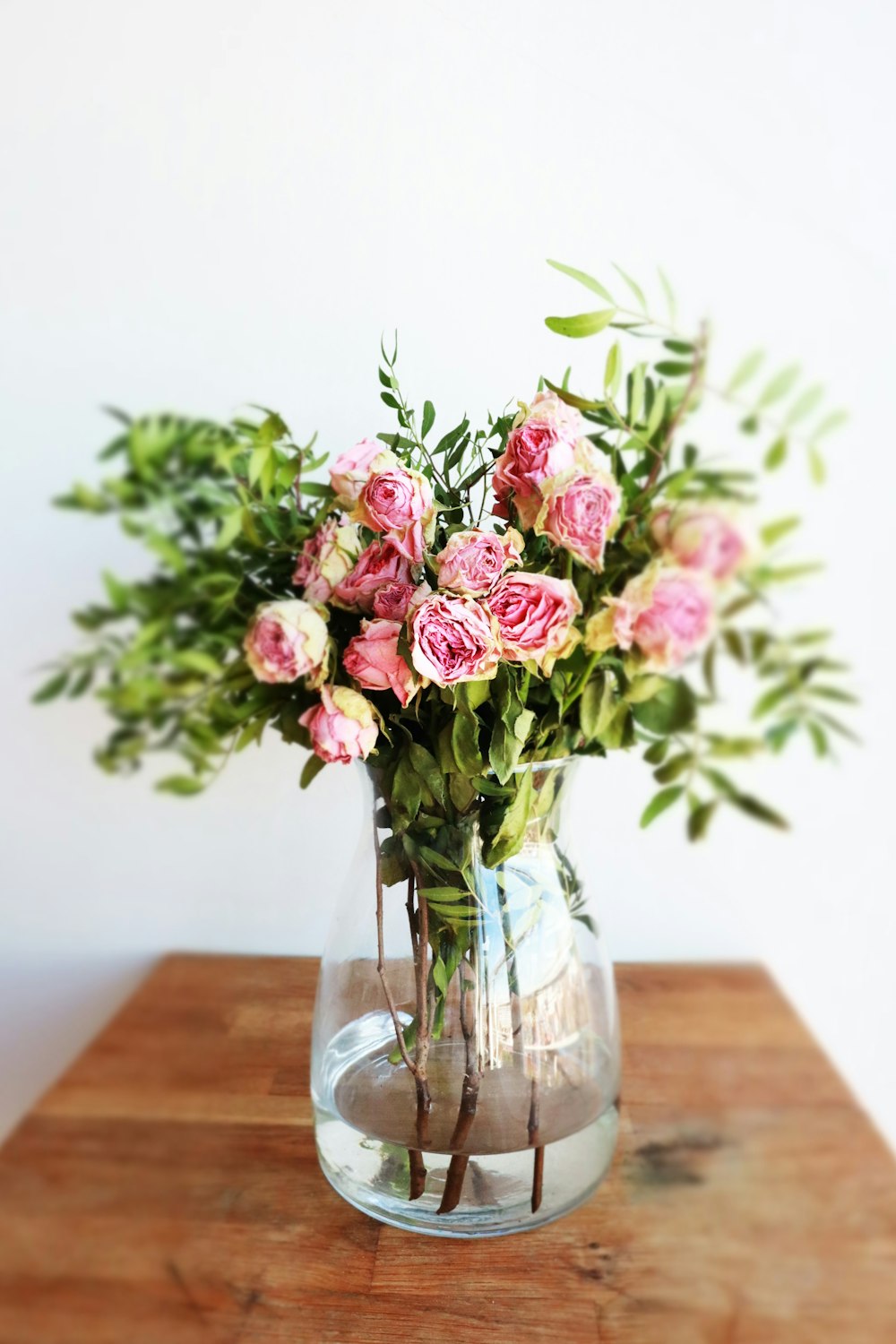 a vase filled with pink flowers on top of a wooden table