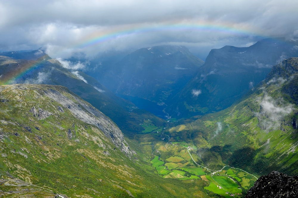 a rainbow in the sky over a valley