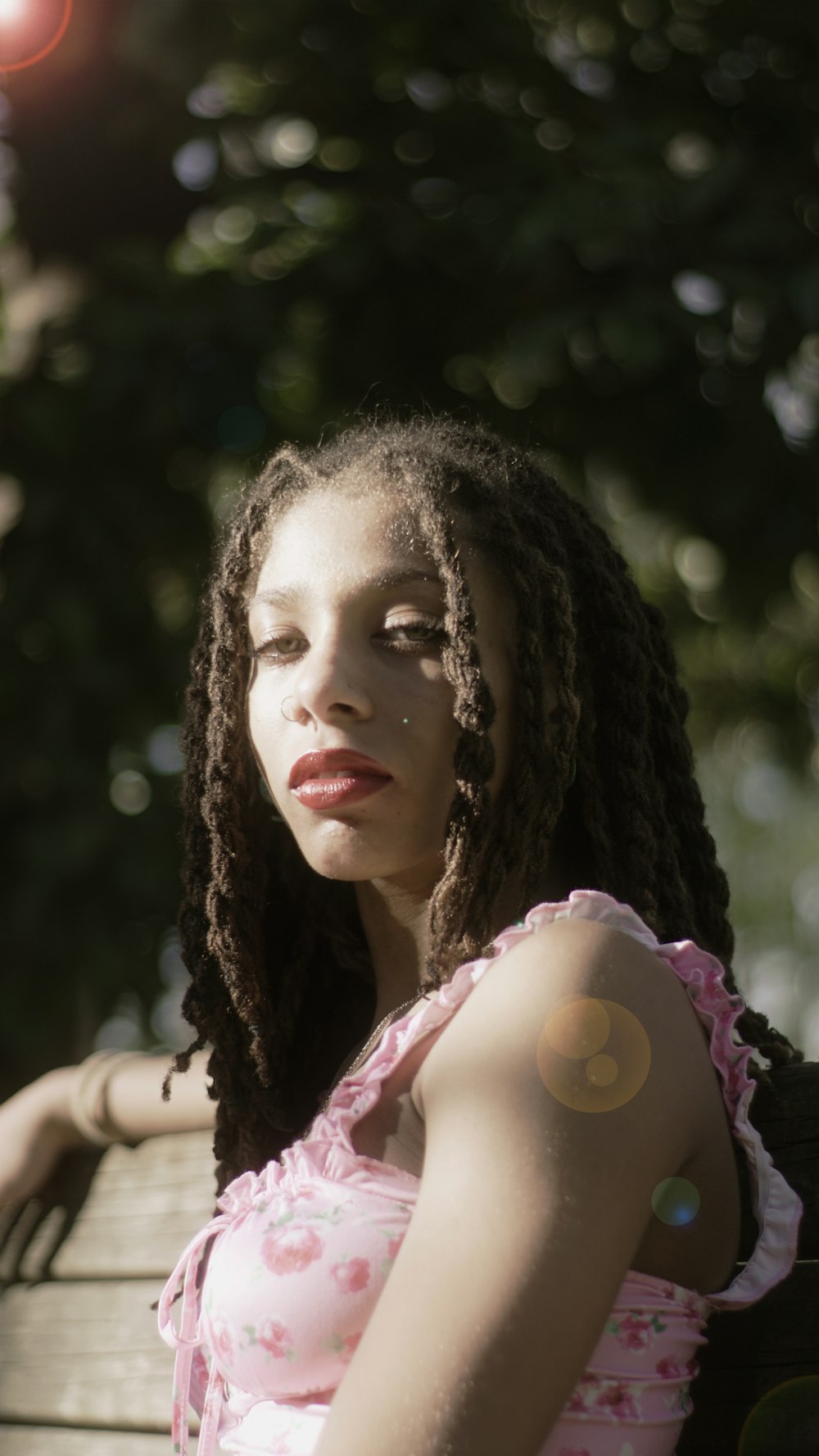 a woman with dreadlocks sitting on a bench