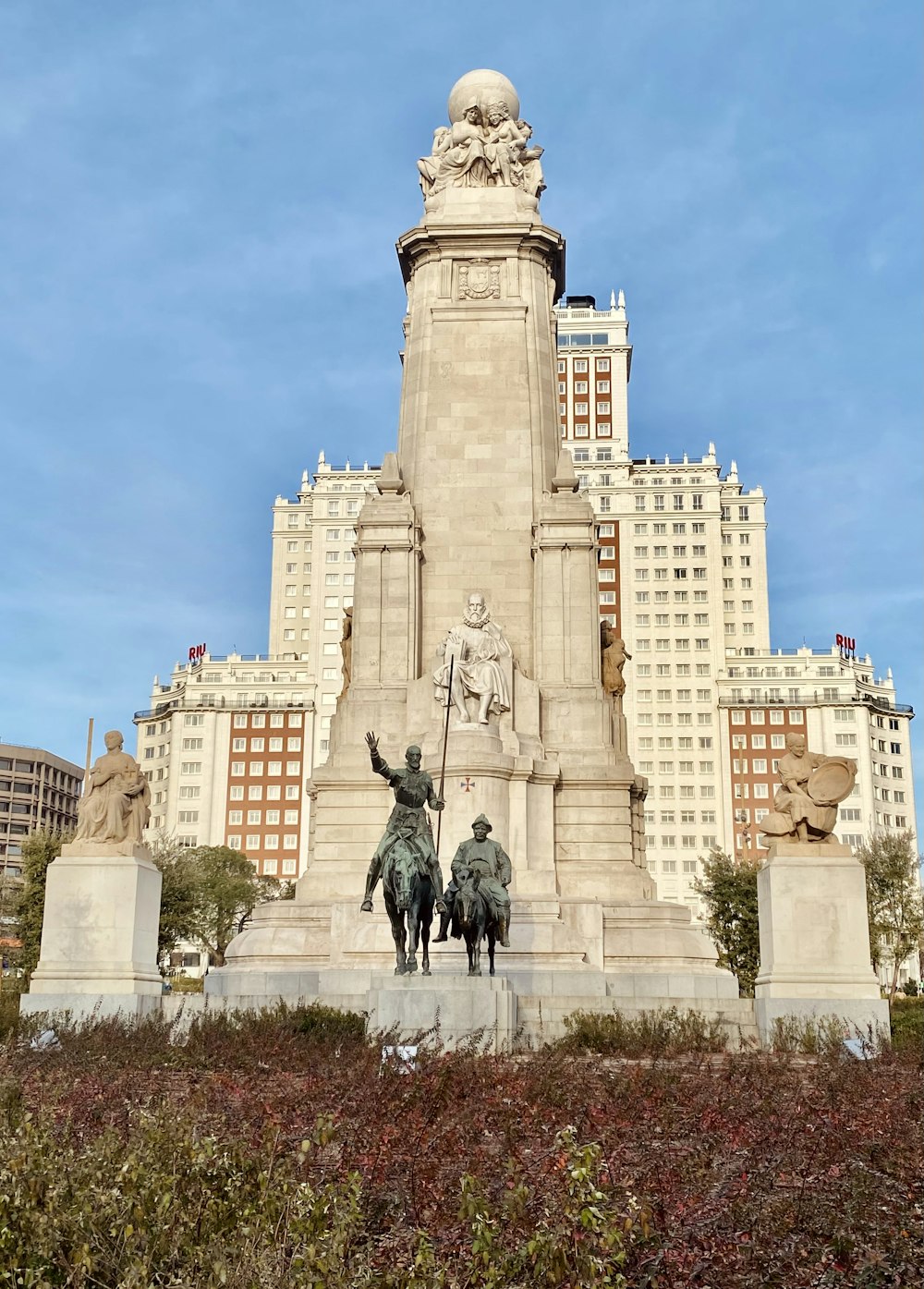 a statue of two men riding horses in front of a tall building