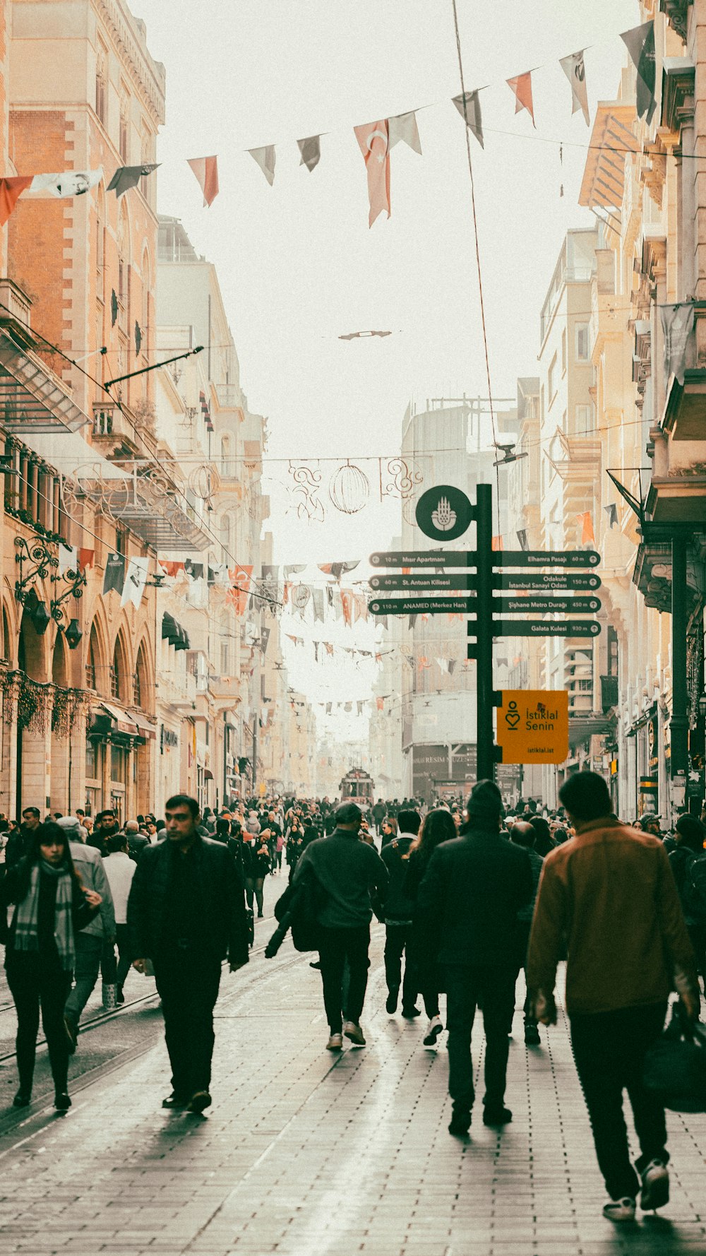 a crowd of people walking down a street next to tall buildings