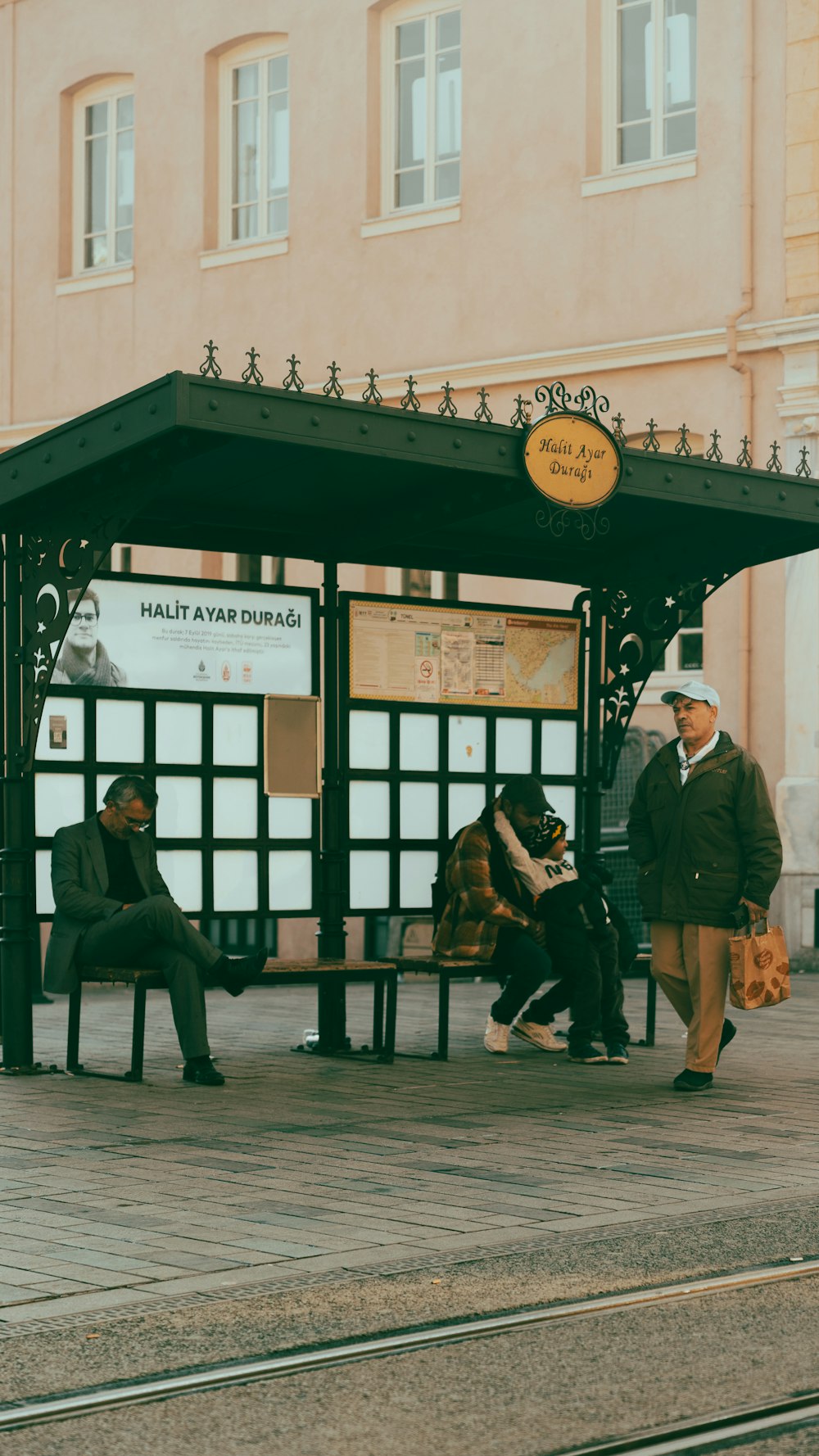 a group of people sitting on a bench next to a train station