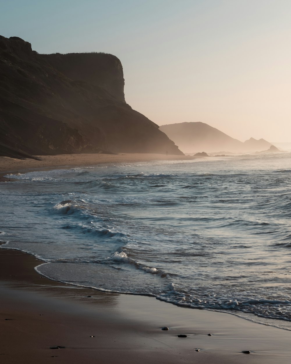 a sandy beach with waves coming in to shore