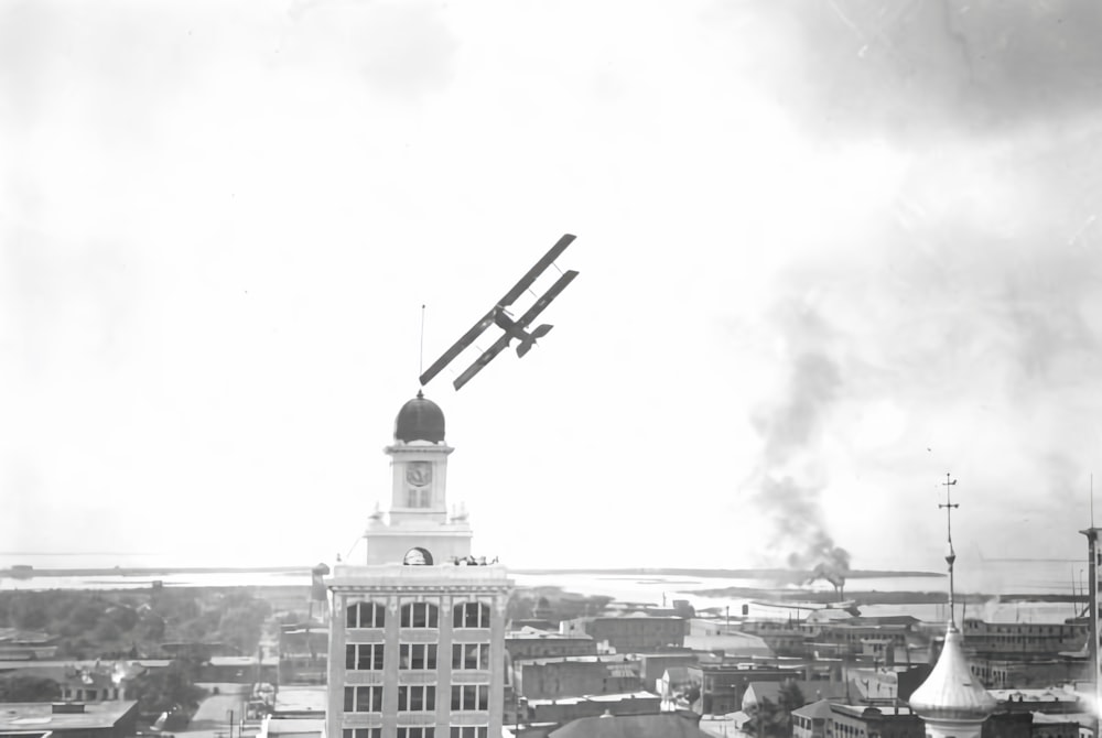 an old photo of a plane flying over a city