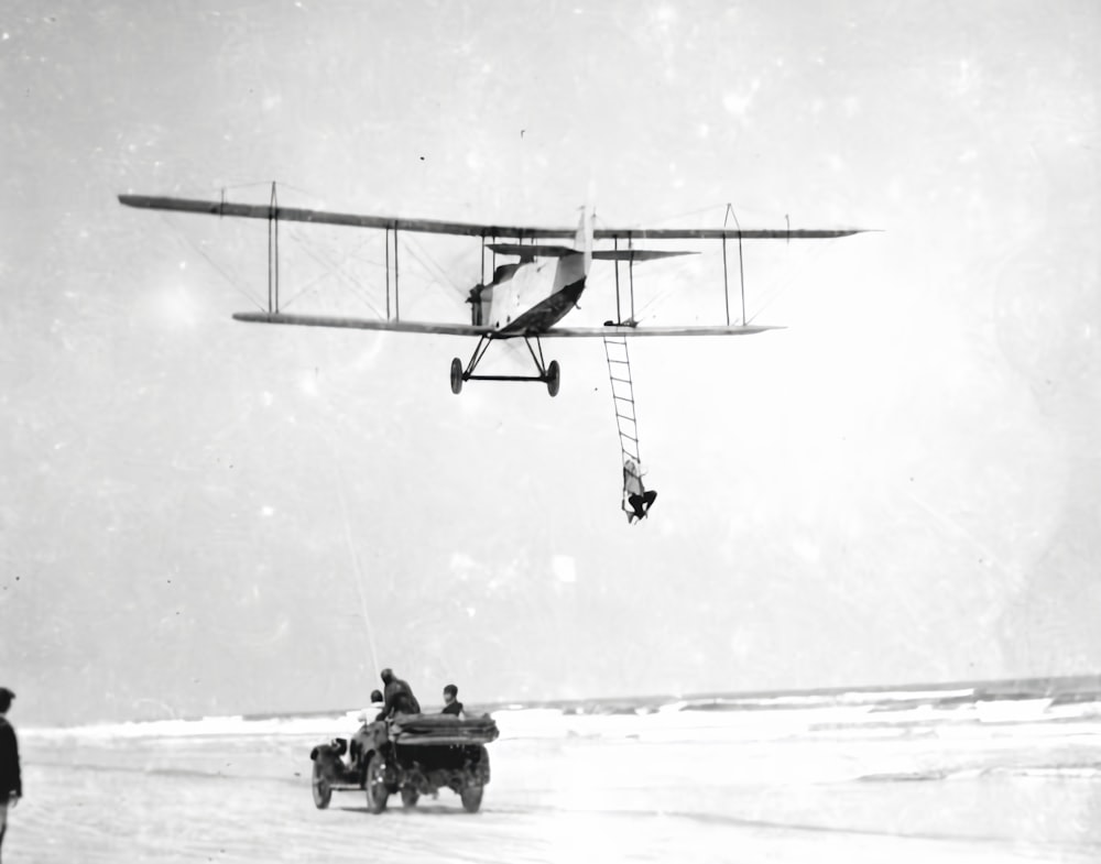 a plane flying over a beach next to a car