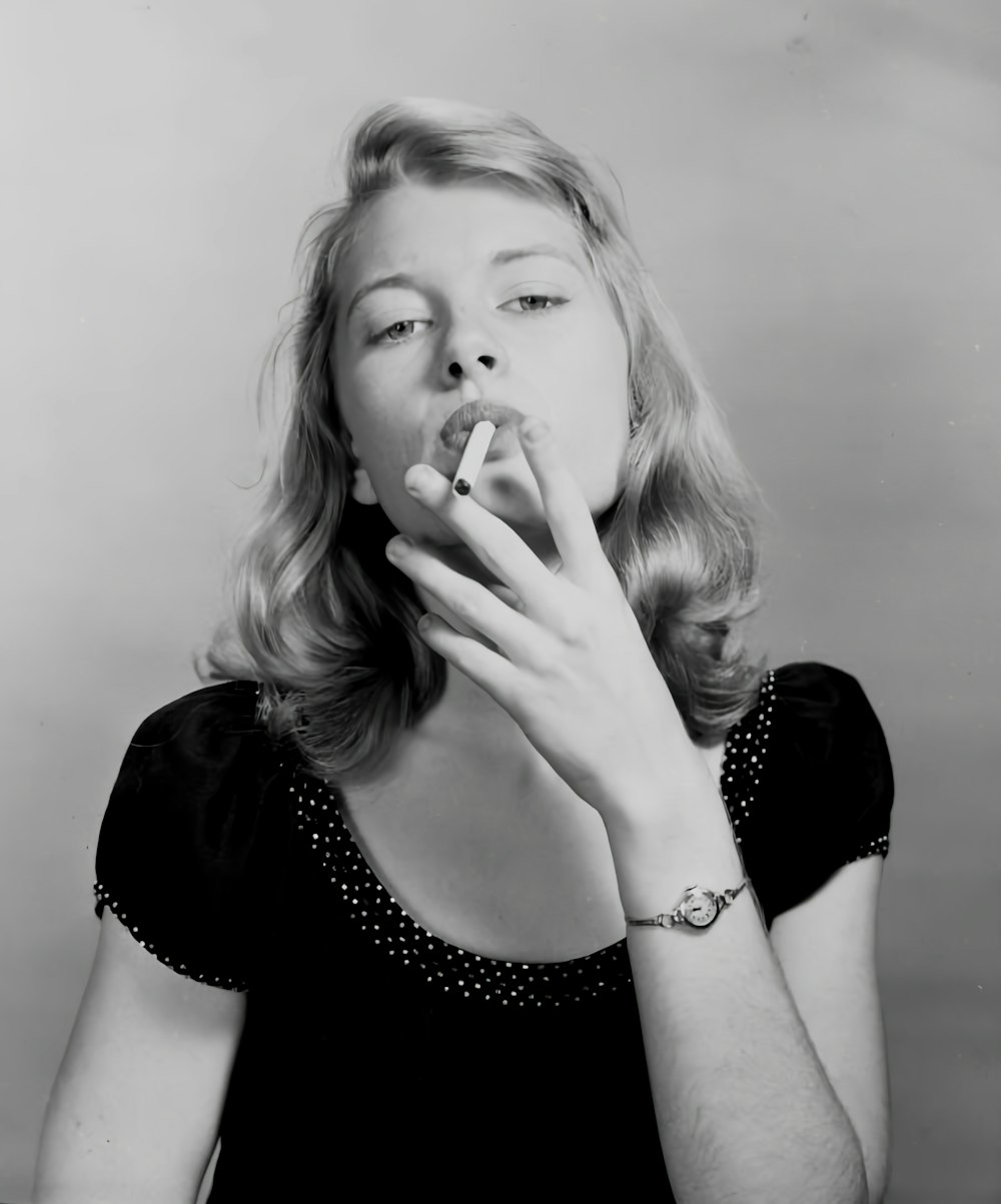a woman smoking a cigarette in a black dress