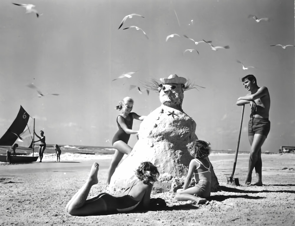 a black and white photo of a group of people on a beach