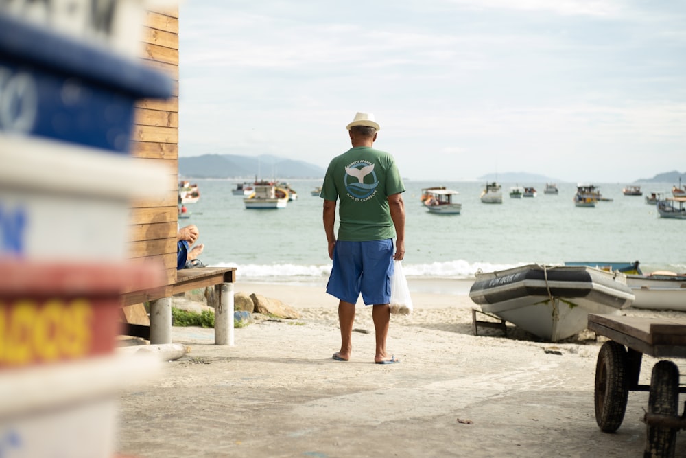 Un hombre parado en una playa junto a un cuerpo de agua