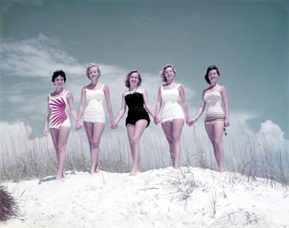 a group of women standing on top of a sandy beach