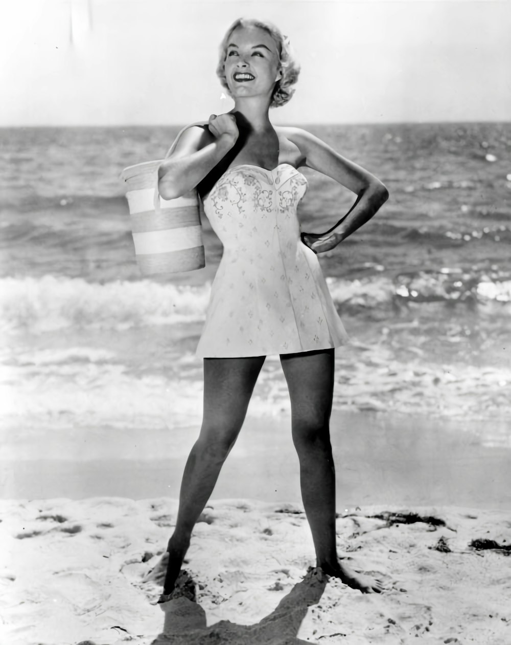 a black and white photo of a woman on the beach