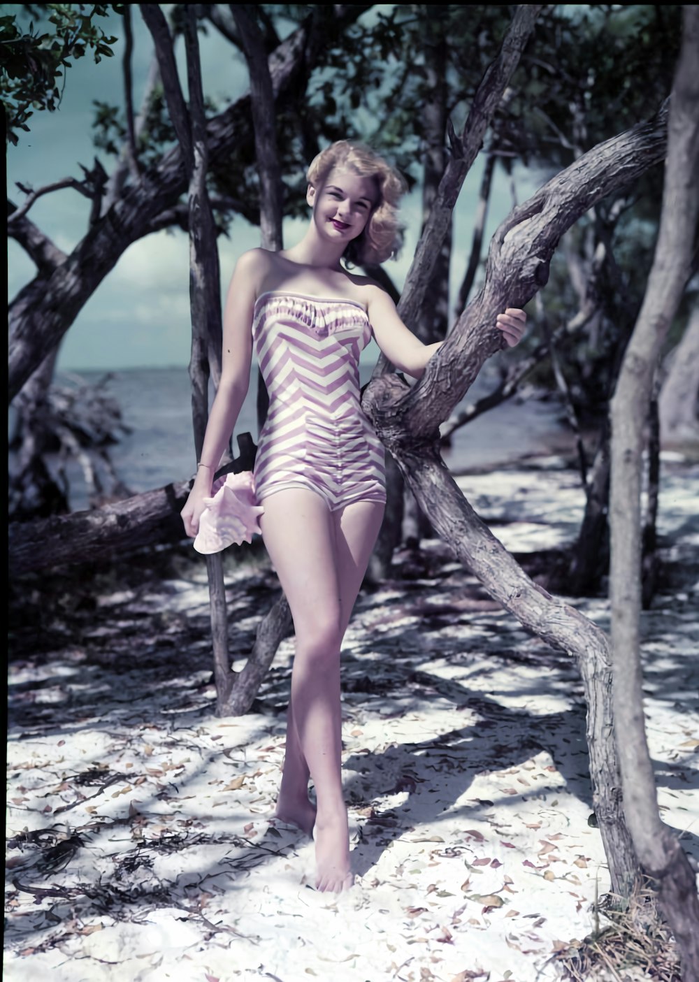 a woman in a bathing suit standing next to a tree