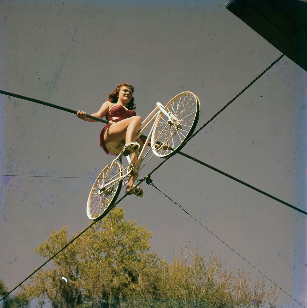a woman riding a bike on top of a wire