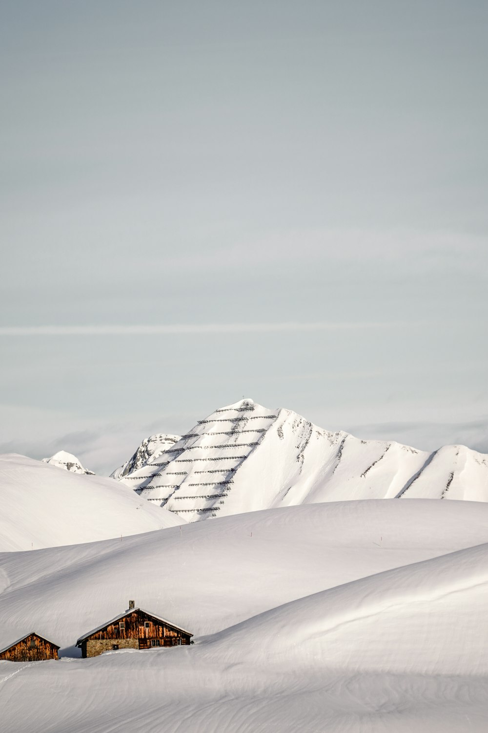 a snow covered mountain with a house in the foreground