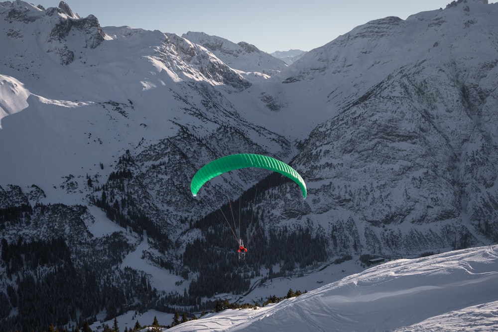 a person paragliding over a snow covered mountain