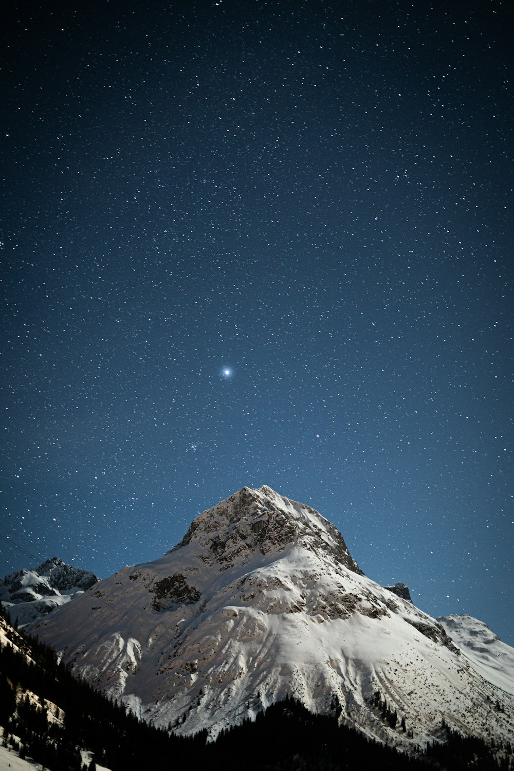 Una montaña cubierta de nieve bajo un cielo lleno de estrellas