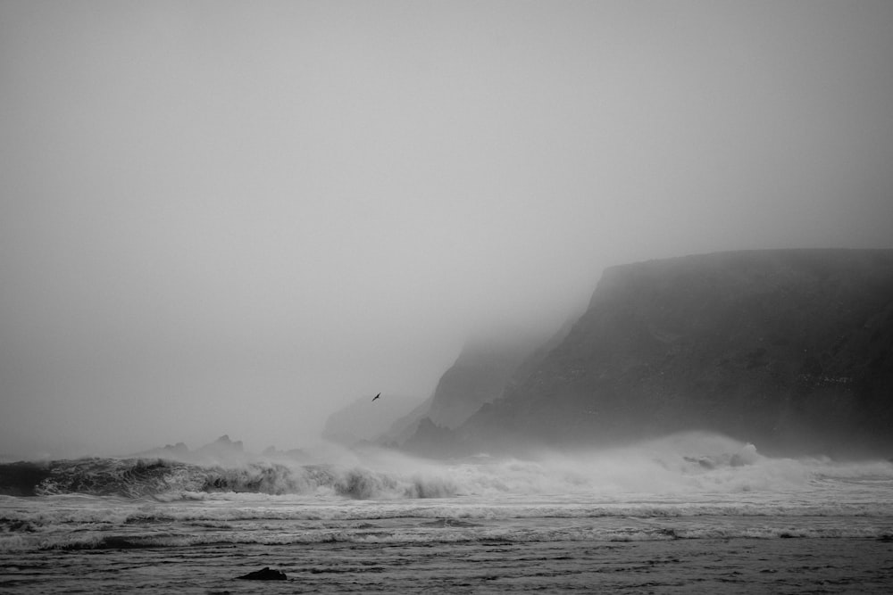 Una foto in bianco e nero delle onde che si infrangono sulla spiaggia