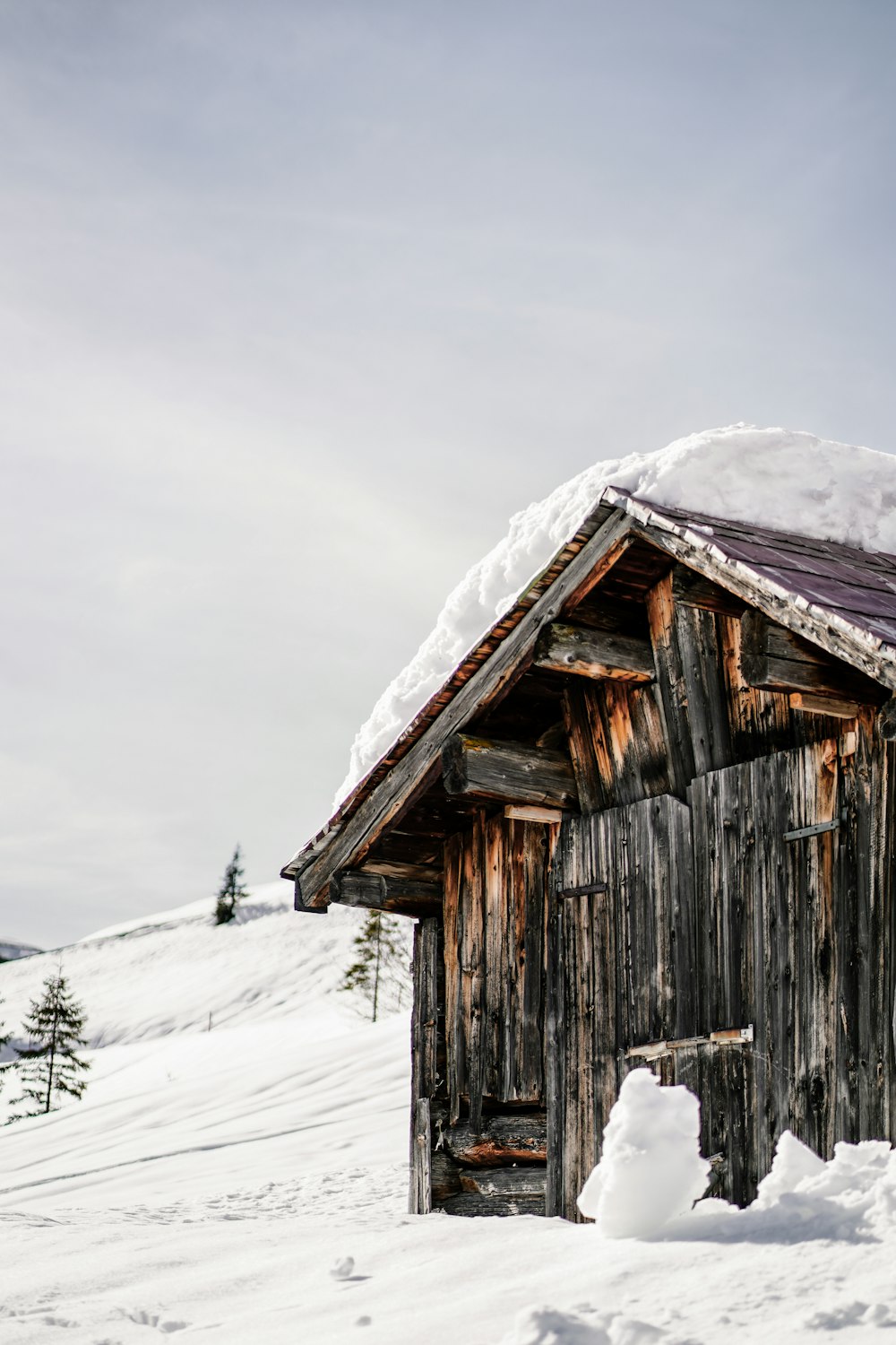 a small wooden building with snow on top of it