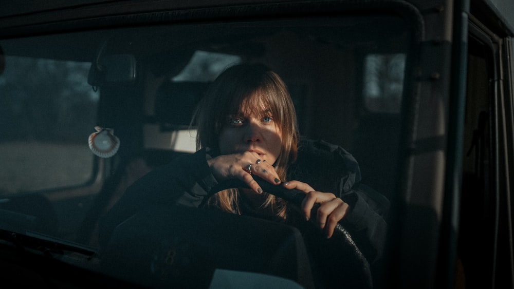 a woman sitting in a car smoking a cigarette