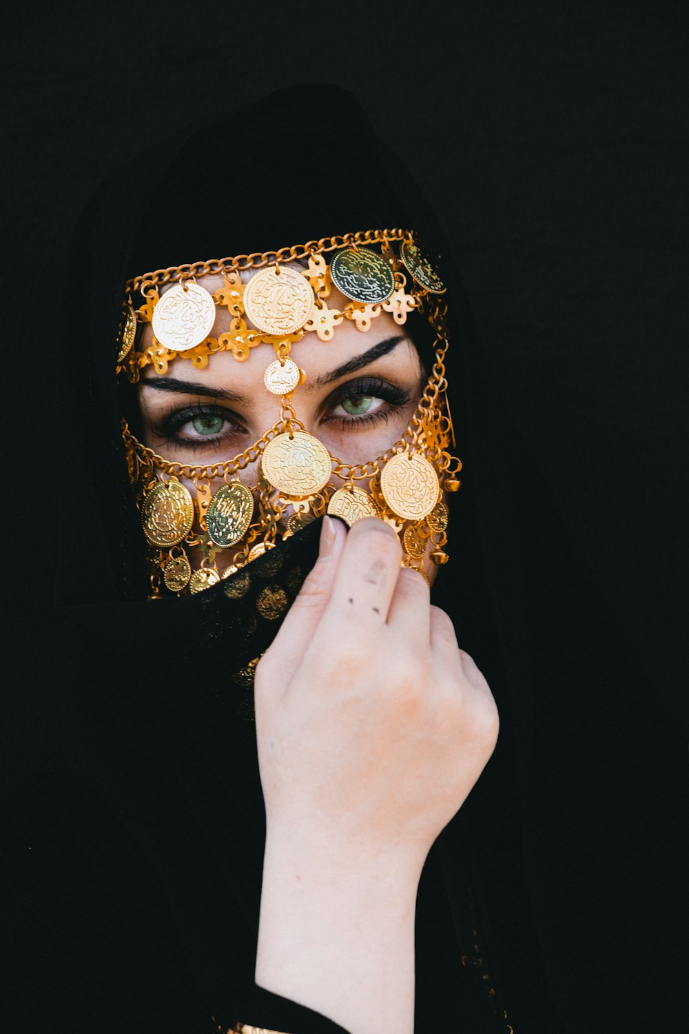 a woman wearing a black veil and a gold mask