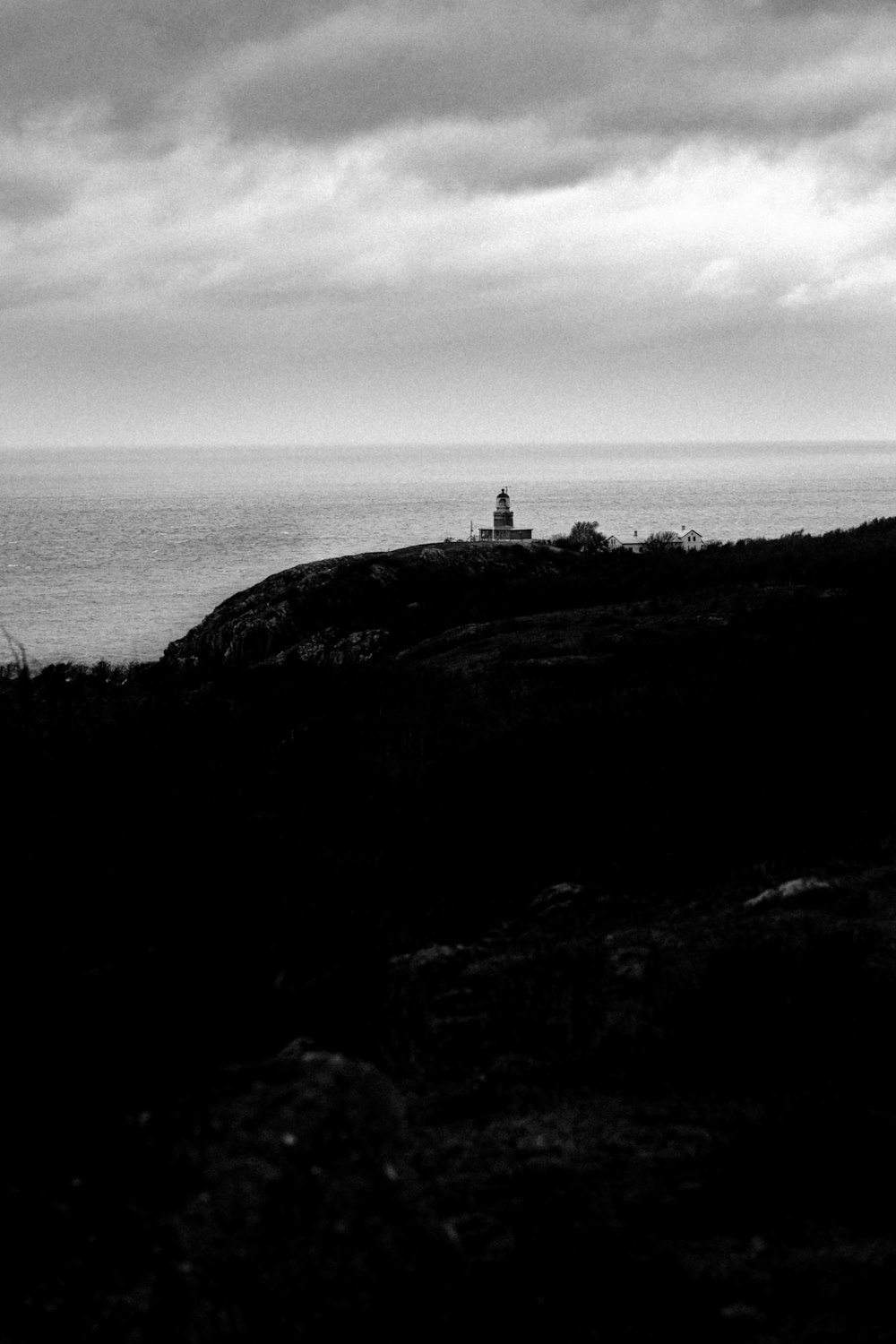 a black and white photo of a lighthouse on a hill