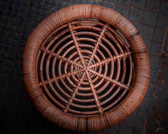 A rattan high bar stool positioned beside the wrought iron bar table, showcasing its woven texture.