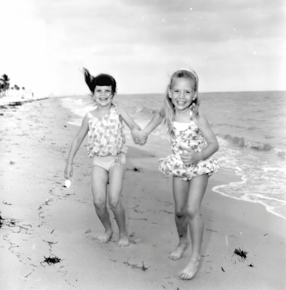 two little girls walking on the beach holding hands