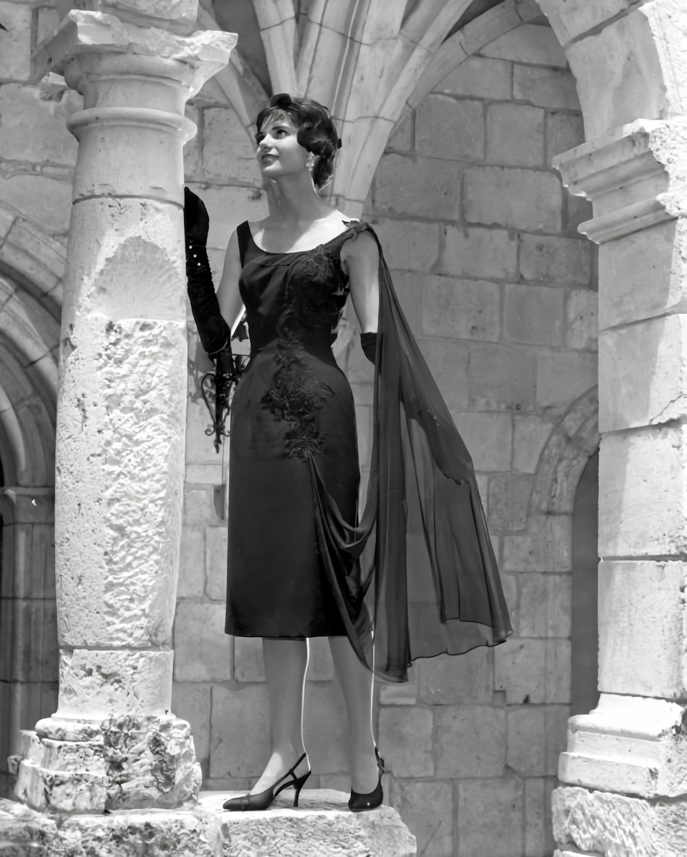 a woman in a dress standing on a ledge