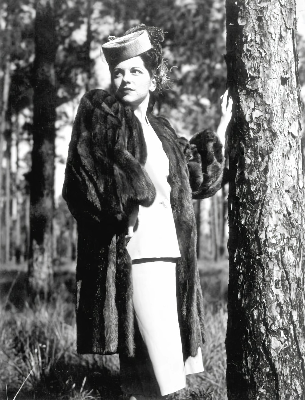 a woman standing next to a tree in a forest