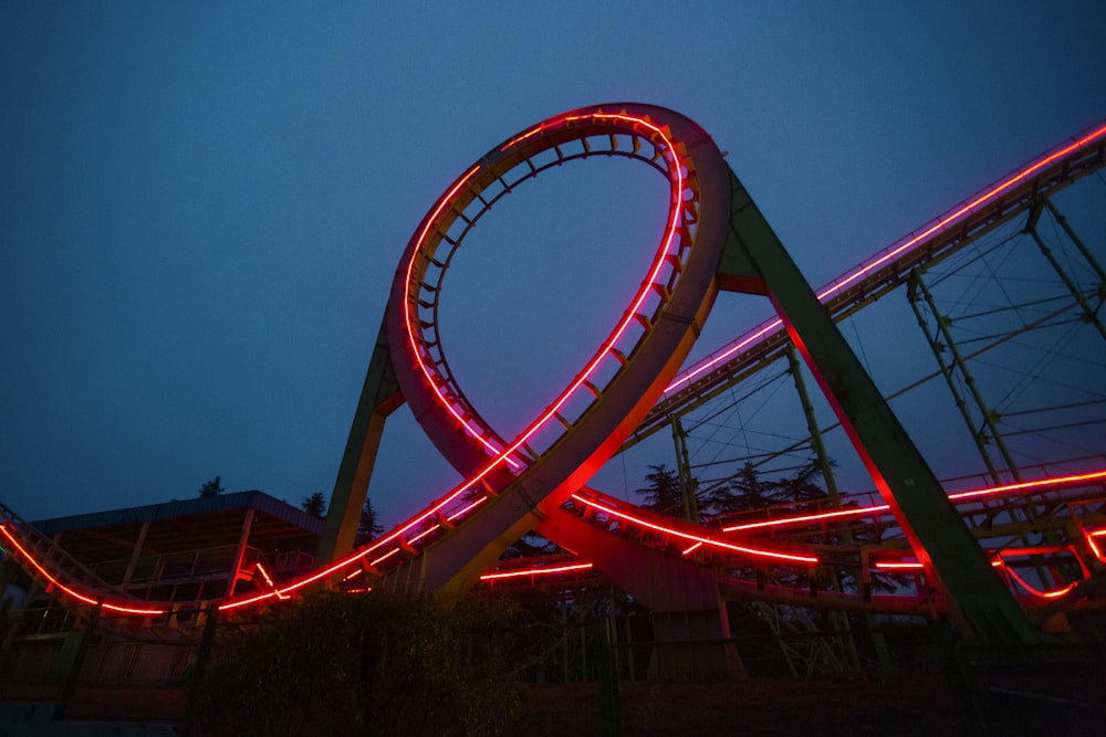 a roller coaster lit up at night with red lights