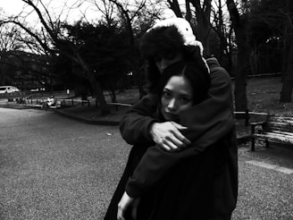A black and white photo of grandparents holding hands on a park bench.