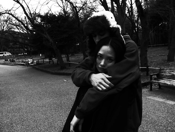 A serene black and white photo of an elderly couple holding hands on a park bench.
