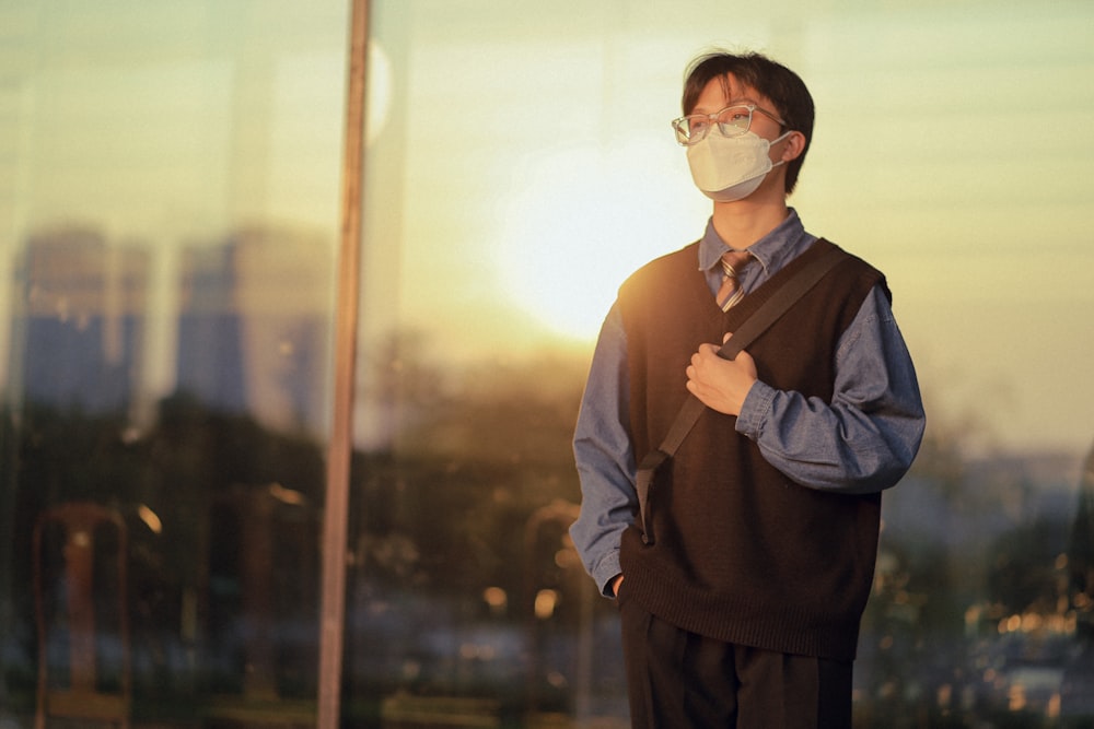 a man wearing a face mask standing in front of a window