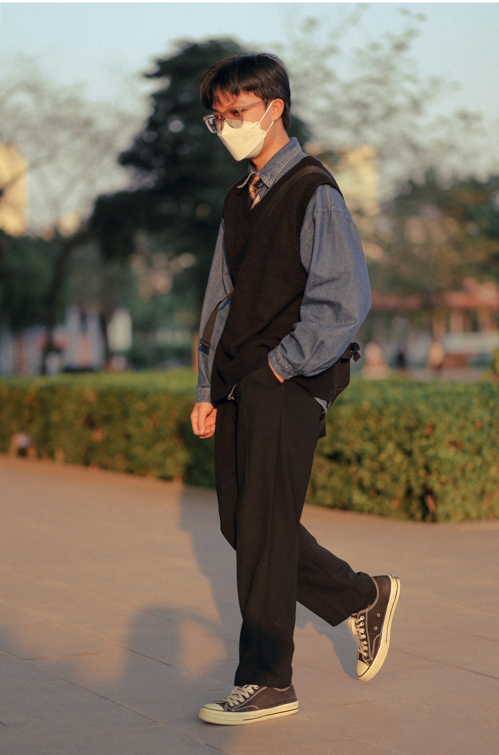 a man walking down a sidewalk wearing a face mask