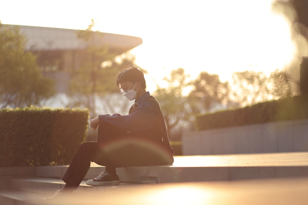 a man sitting on a step wearing a face mask