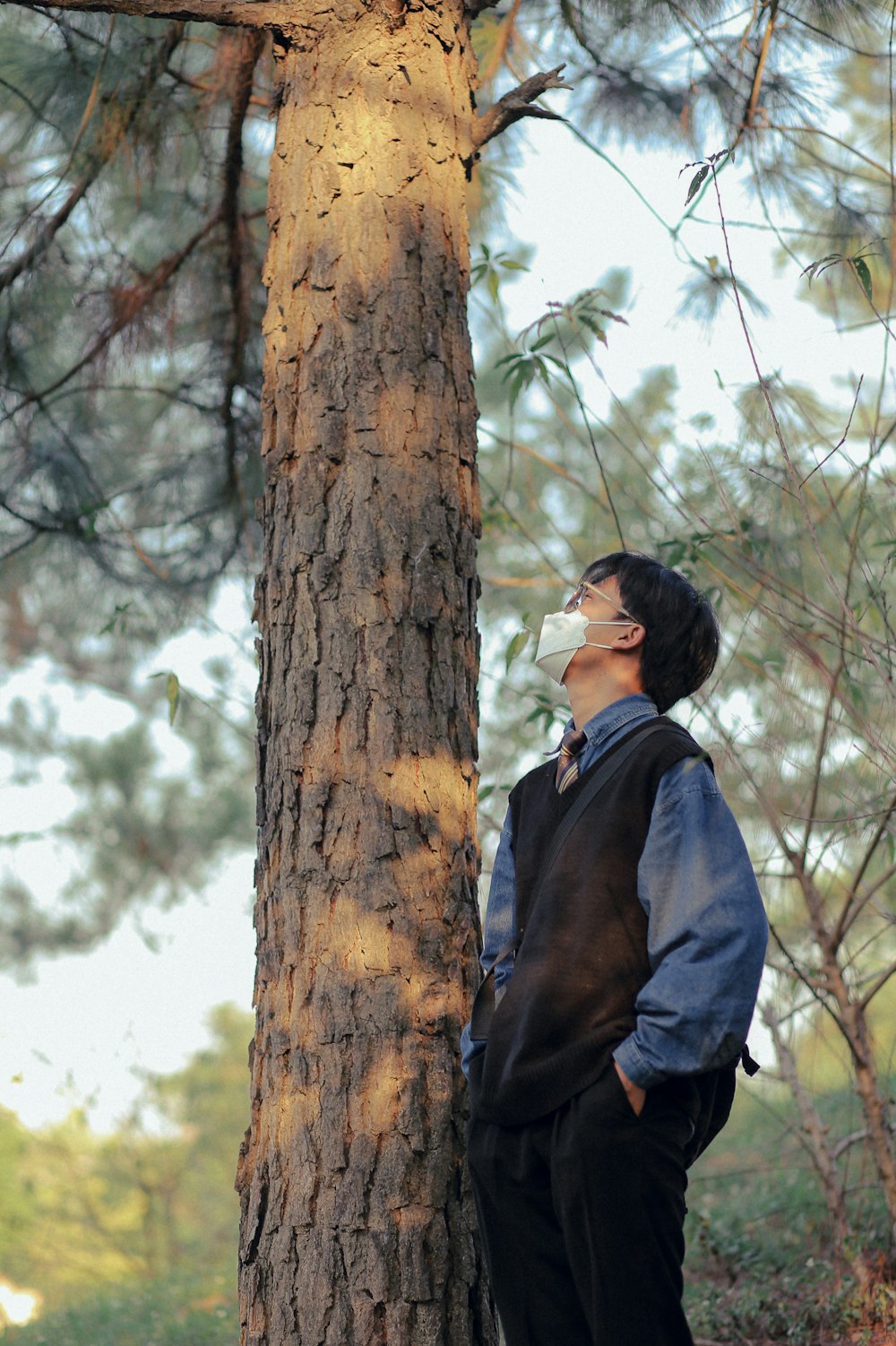 a man standing next to a tree in a forest