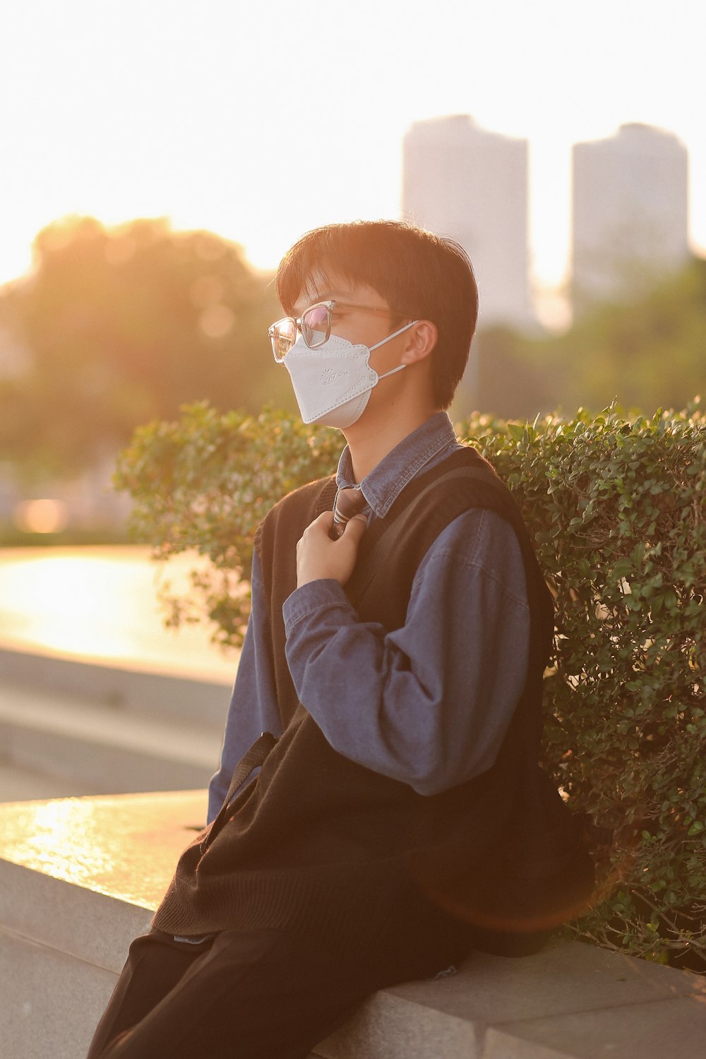 a man sitting on a ledge wearing a face mask