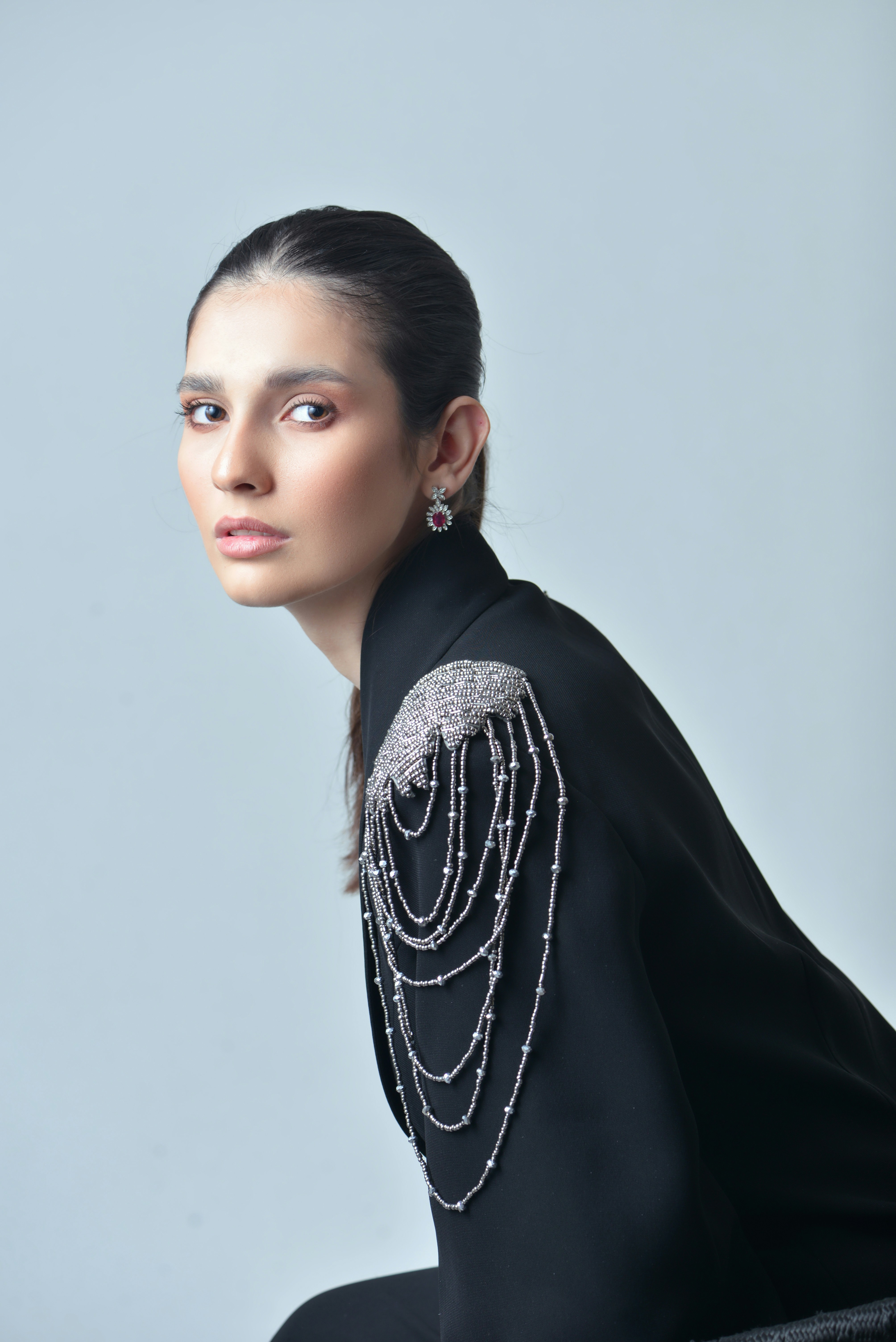 a woman wearing a black top with silver chains on it