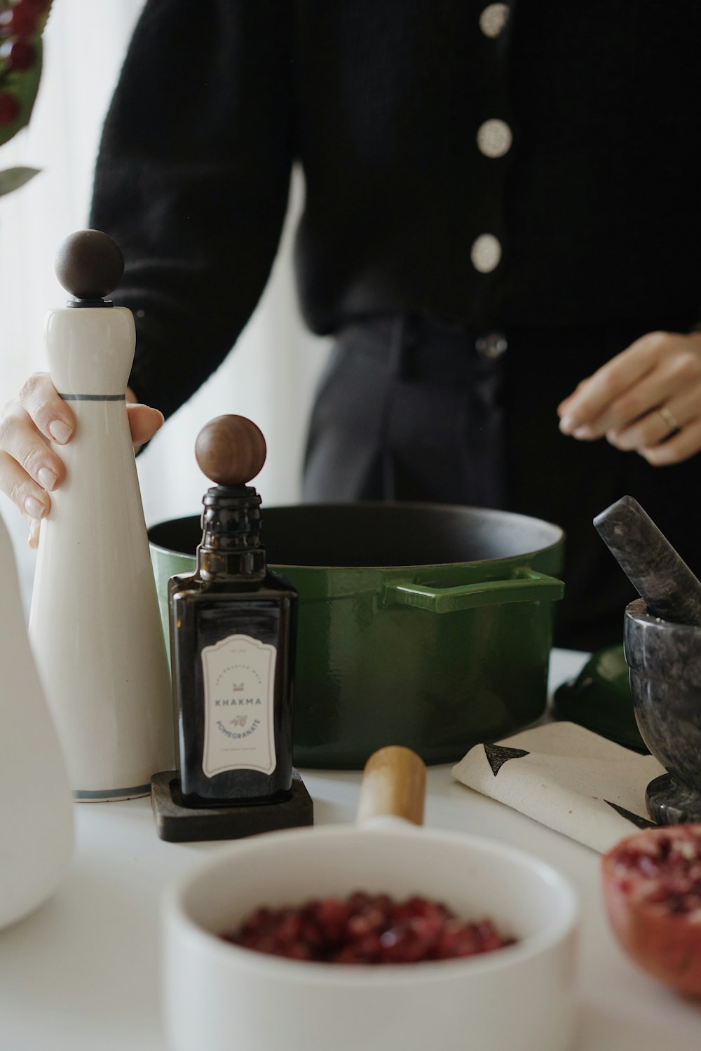 a person standing over a table with a bowl of food and a bottle of wine