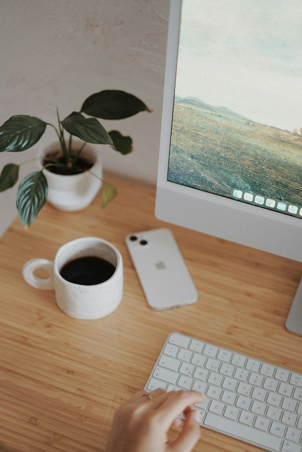 a person typing on a computer keyboard next to a cup of coffee