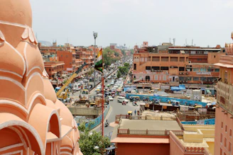 A warm portrait of Samay Singh Bairwa standing in front of a Jaipur cityscape blending modern buildings with traditional architecture.