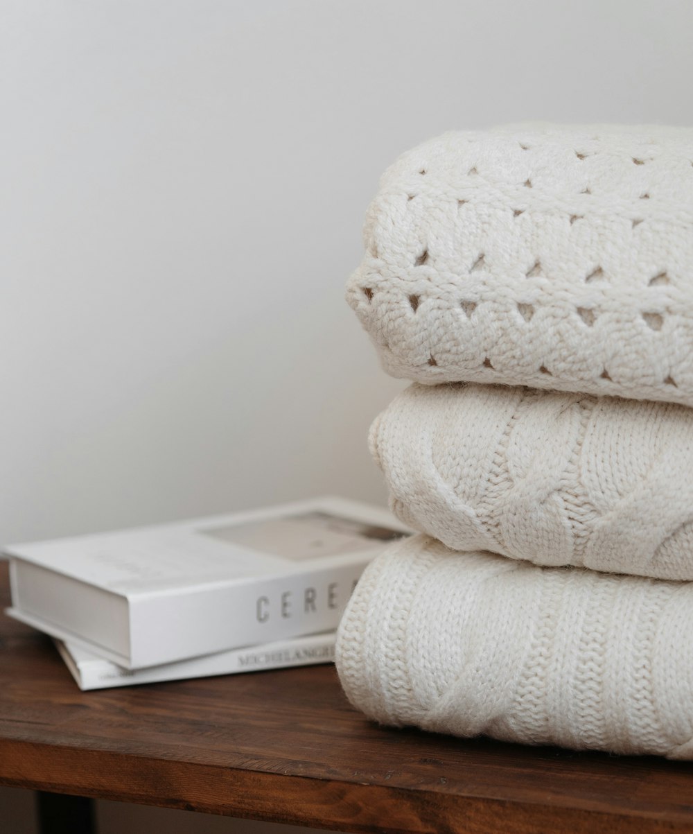 a stack of white blankets sitting on top of a wooden table