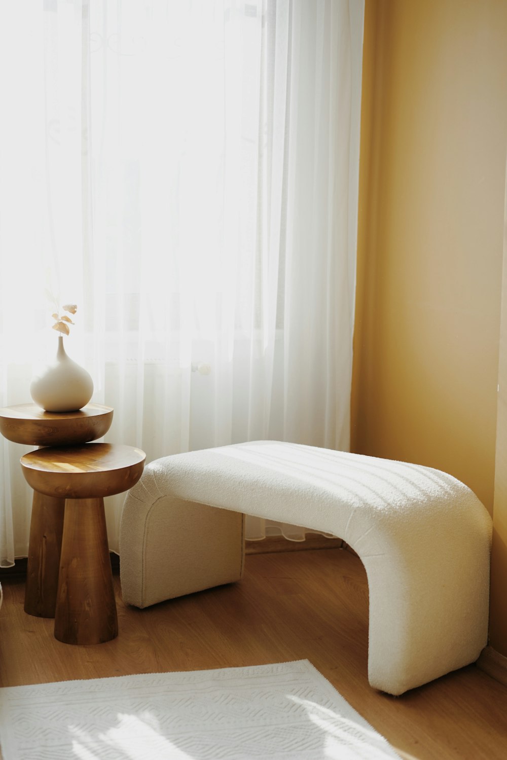 a white bench sitting in a living room next to a window