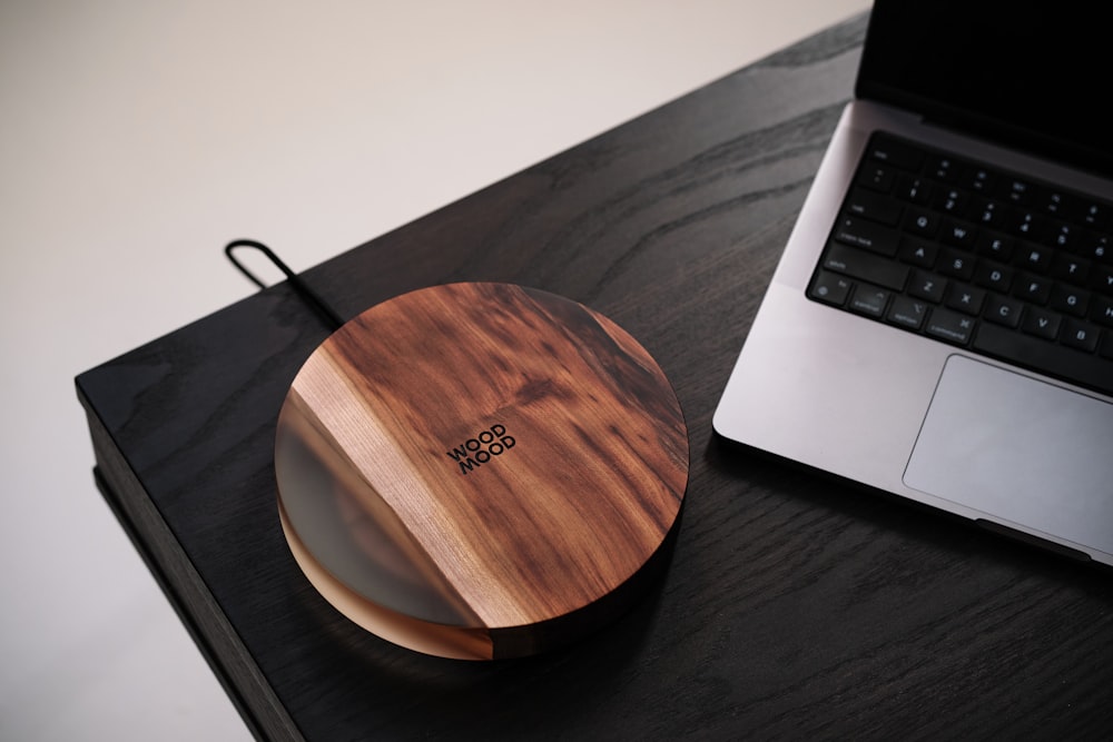 a wooden mouse pad sitting next to a laptop