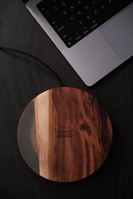 Close-up of a sleek wireless charger glowing with blue electric light on a dark surface.