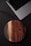 Close-up of a person holding a sleek wireless charger on a wooden desk.
