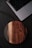 Close-up of a person holding a sleek wireless charger on a wooden desk.