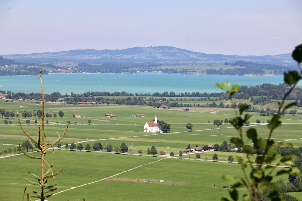a view of a green field with a lake in the background