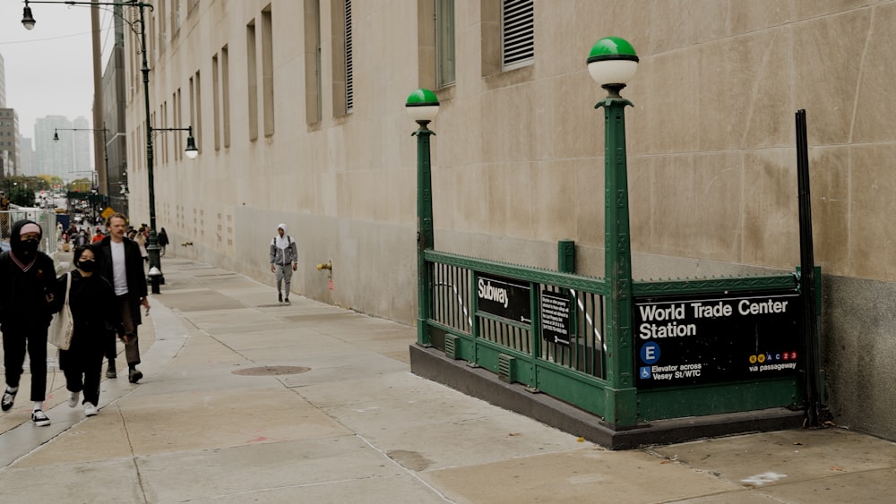 a group of people walking down a sidewalk next to a building