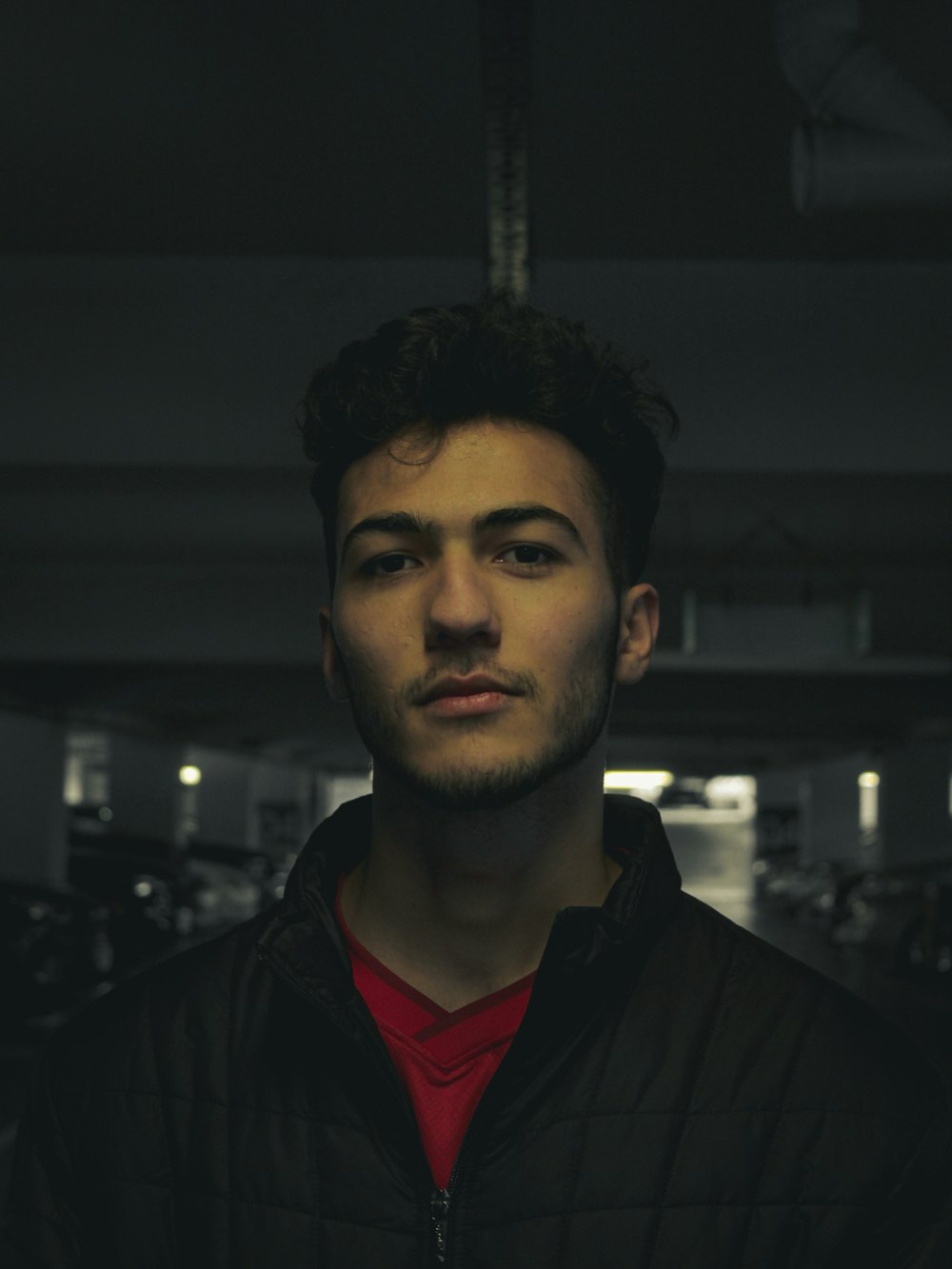 a man in a black jacket standing in a parking garage